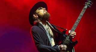 Jane's Addiction's Dave Navarro is open-shirted, wearing a flower in his hat as he is photographed with his signature PRS electric guitars