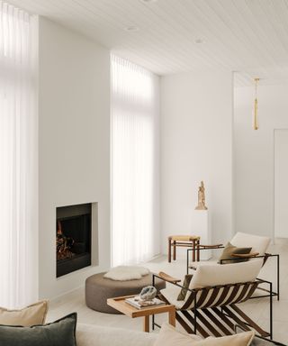 White modern lounge space with modern fireplace, statement striped chair to contrast minimal seating area and pared-back decor
