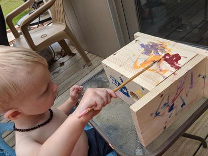 Toddler Painting A Wooden Birdhouse