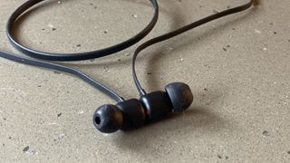 A close up of the earbuds of the Beats Flex wireless earphones in black on a marble surface