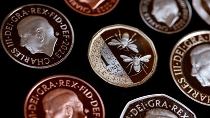 The reverse face of a one-pound coin, featuring a design of bees, displayed by the Royal Mint in London, UK
