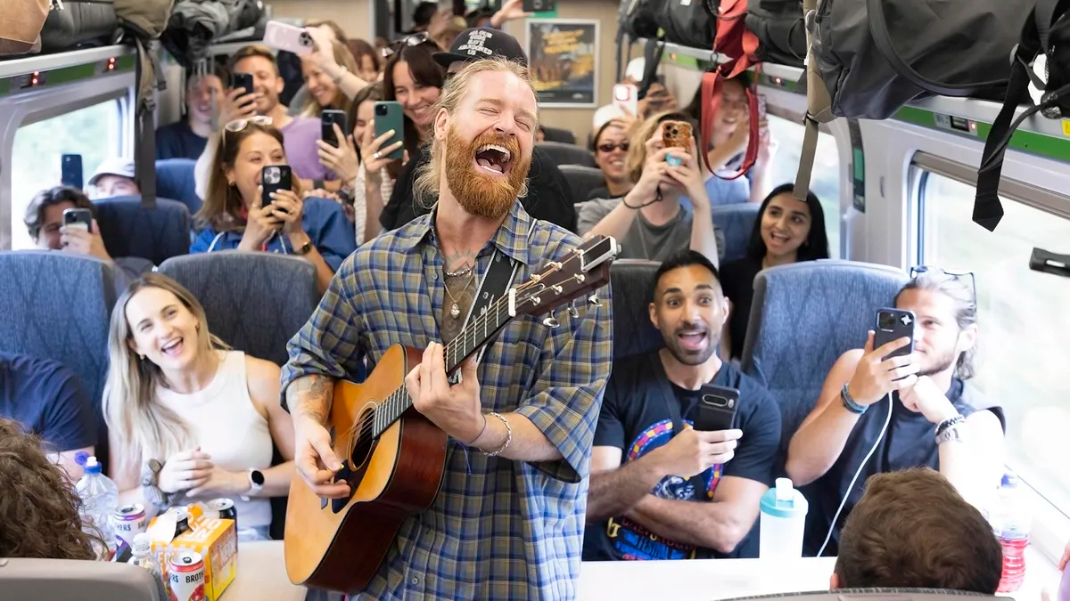 Photo of musician Sam Ryder performing an impromptu gig onboard a train service traveling from Paddington Station to Glastonbury, UK.