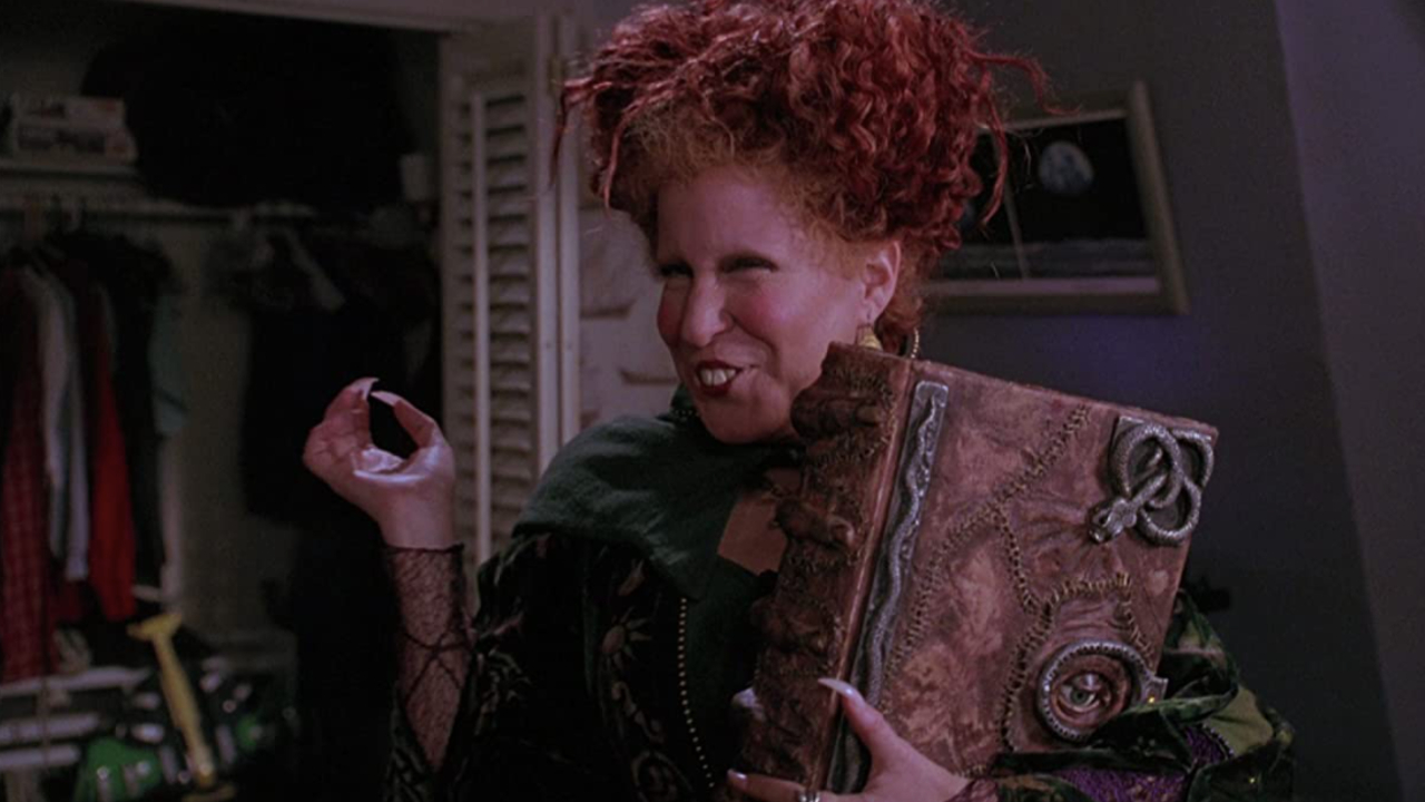 Bette Midler hält Buch mit einem bösen Lächeln in Hocus Pocus.