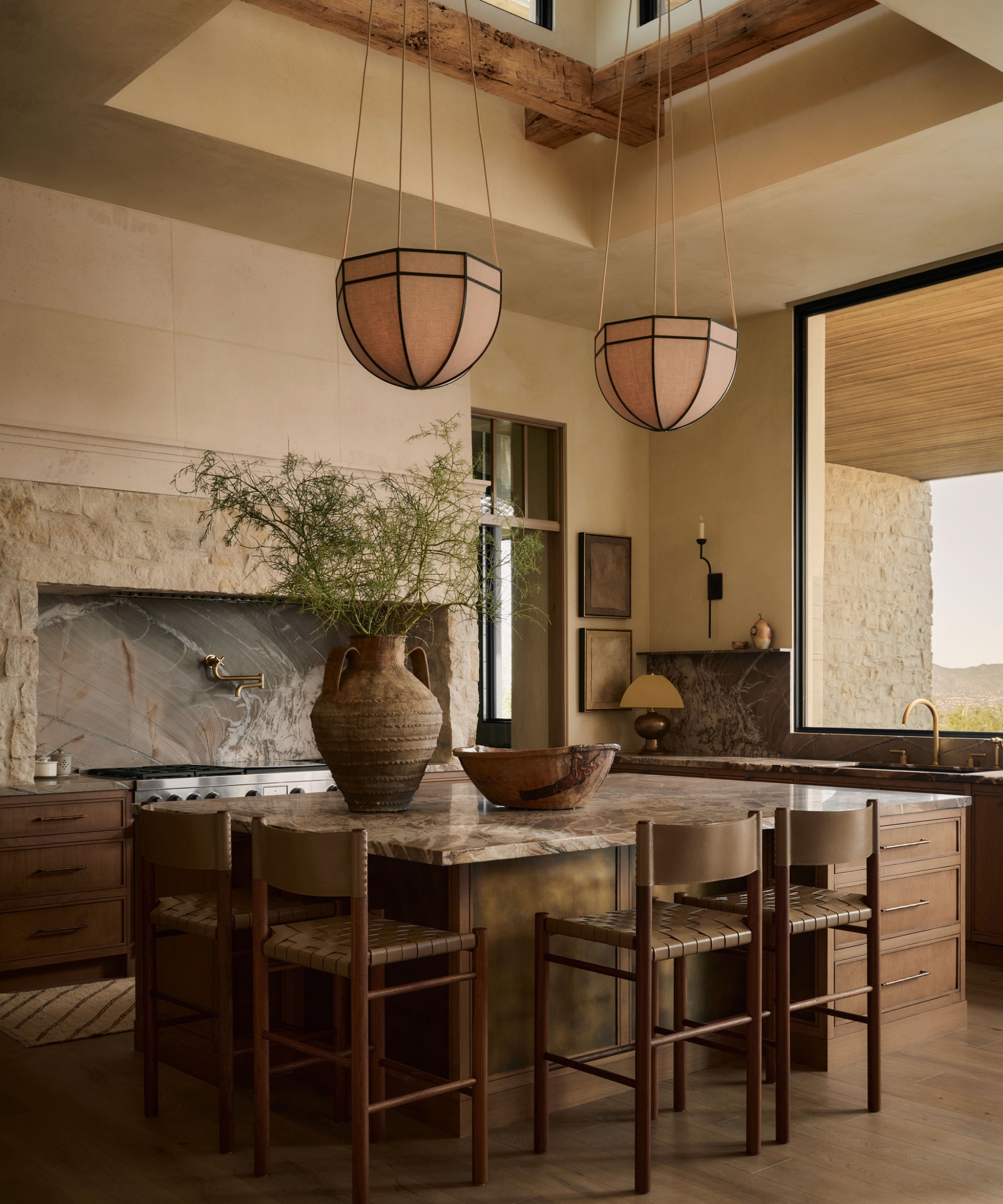 A warm neutral kitchen with a wooden island, stone countertops, a vaulted ceiling with a skylight, and a large window above the sink to maximize the panoramic Arizona views