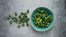 Cucamelons in a bowl and strewn over a grey marbled table top