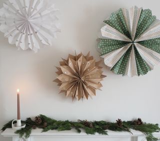 main image of diy Christmas paper bag decorations, three above a mantel with fir tree foliage, pine cones and candle