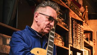 Portrait of Richard Hawley in sunglasses with his vintage Gretsch guitars