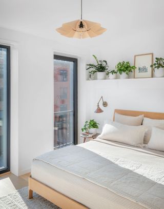 Small white bedroom with house plants and large windows