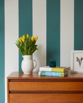 Turquoise stripes on a wall with a vase full of flowers on a table