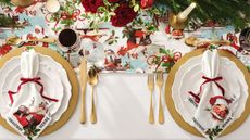 Christmas tablescape with gold flatware and Norman Rockwell prints on napkins and runner