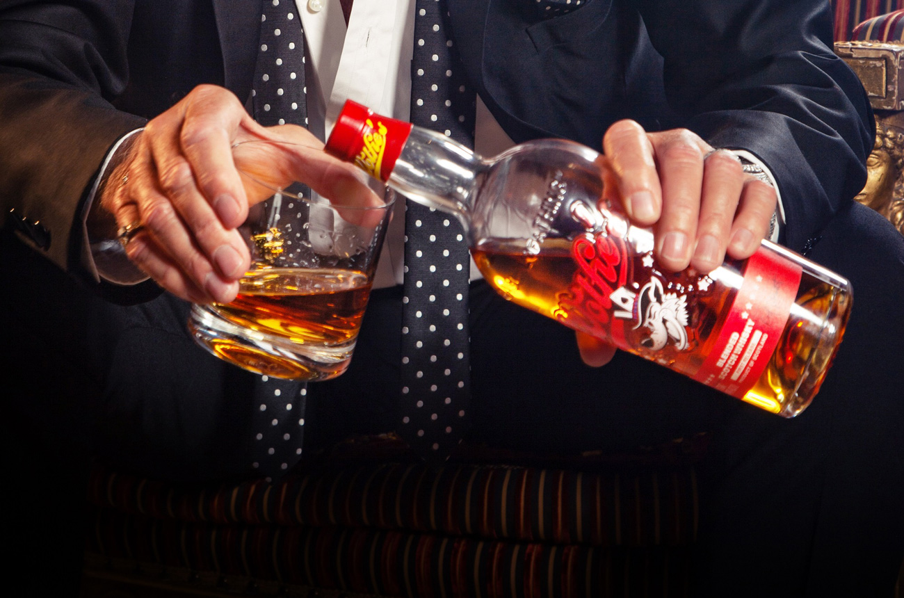 Hands holding a bottle of whisky and a glass