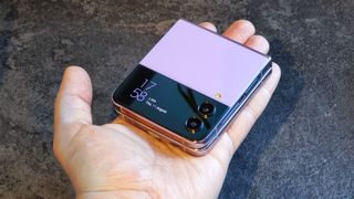 En hand holder en lukket Samsung Galaxy Z Flip 4 i en lyslilla farge.