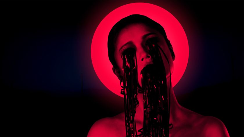 A woman bathed i nred light with VHS reel coming out of her eyes and mouth