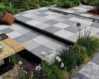 black, white and grey paved patio with flowerbeds