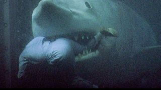 Still from a Jaws movie. Here we see a giant great white shark chomping on a man wearing a blue jumpsuit.