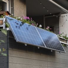 Angled solar panels installed on a balcony with flowers and festoon lights in Dusseldorf, Germany