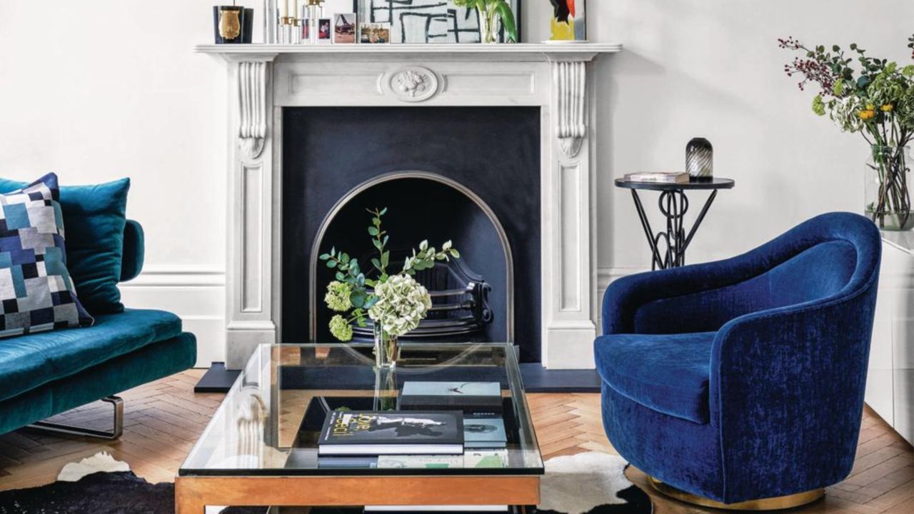 White living room with hard wood floors, a black classic fireplace, and electric blue accent chairs