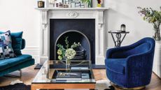 White living room with hard wood floors, a black classic fireplace, and electric blue accent chairs