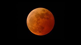 During a total lunar eclipse, the moon appears to turn red while passing through Earth's shadow.