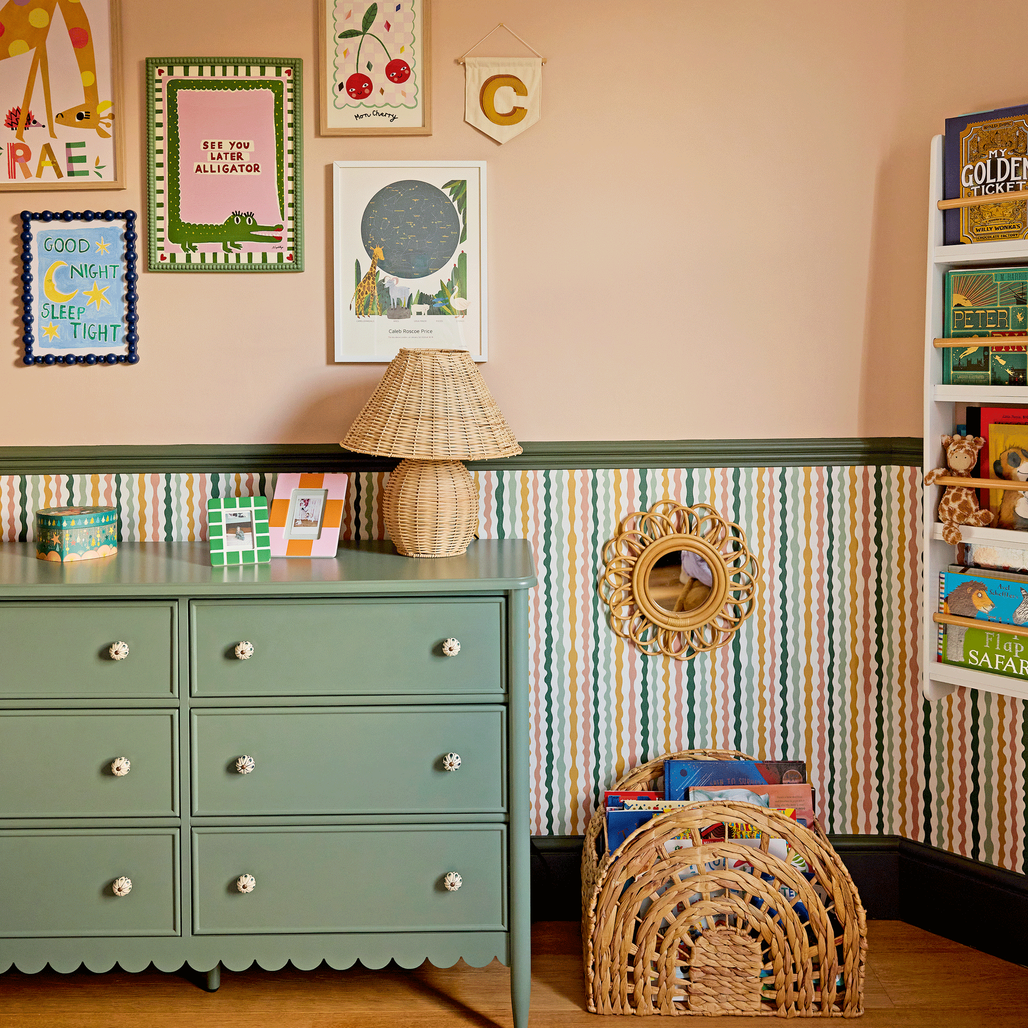 a colourful child's room with a green chest of drawers, striped wallpaper below the dado rail, a gallery wall and wall hung book rack