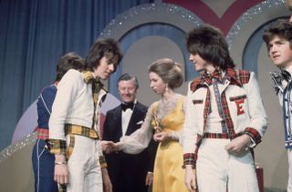 Members of the Bay City Rollers shaking hands with Princess Anne at the Lyceum Ballroom on the occasion of the Carl Alan Awards. On the princess's right is promoter, Eric Morley.