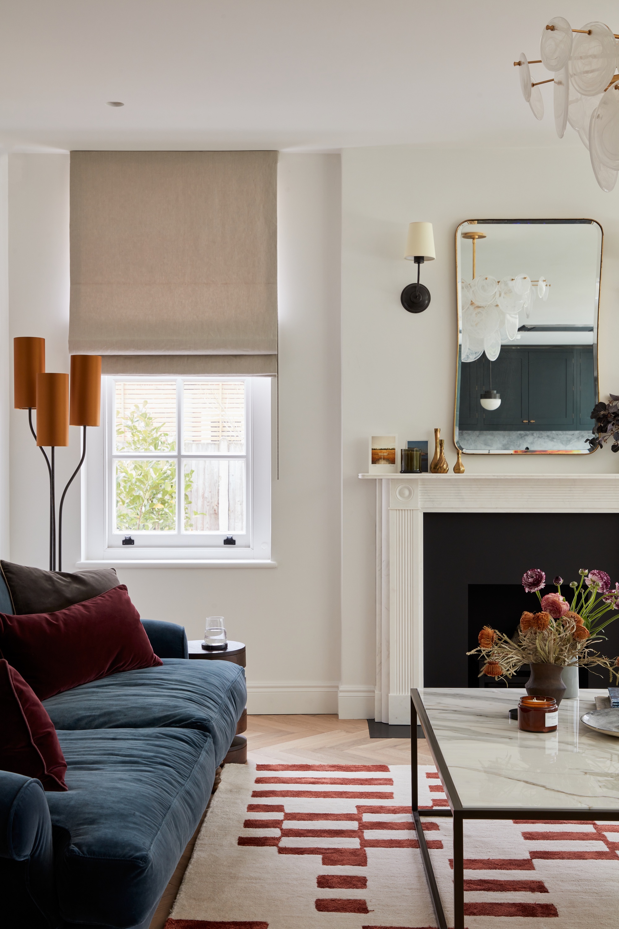 Cream living room with navy sofa and burgundy accents by Imperfect interiors