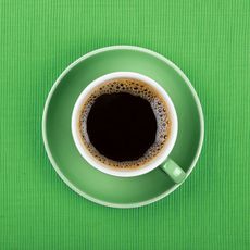 Full black coffee in green cup close up top view