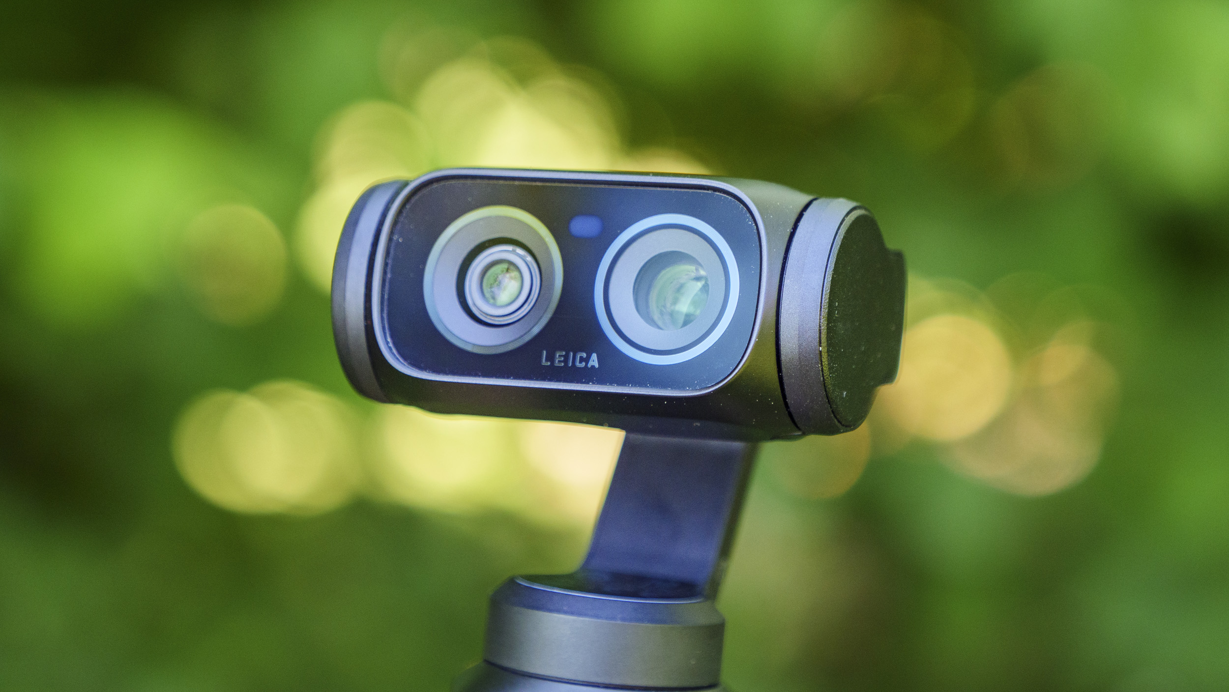 Closeup of the Insta360 Luna Ultra vlogging camera's dual lenses, leafy background