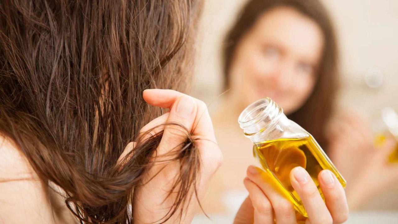 woman putting hair oil on