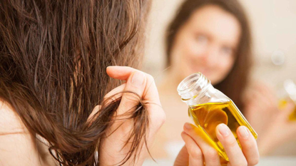 woman putting hair oil on