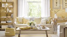 butter yellow living room with a cream sofa and coffee table with white flowers