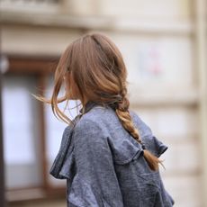 woman wearing denim trench with loose middle plait - different types of hair damage and how to treat it