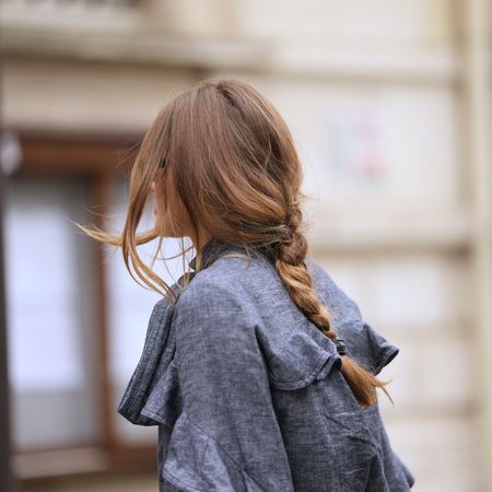 woman wearing denim trench with loose middle plait - different types of hair damage and how to treat it