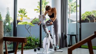 A woman riding an exercise bike at home