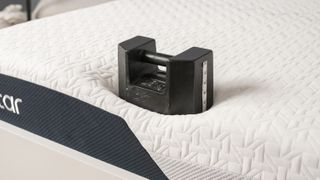 A 25kg black weight is placed on the edge of the Nectar Classic Memory Foam Mattress during an edge support test