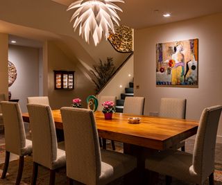 dining room with modern sculptural white pendant light, dining table and chairs, spotlights and stair lights on wall of staircase