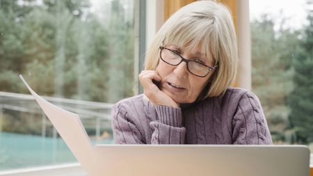 Worried senior woman examining a bill 