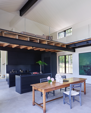 Black kitchen with concrete flooring and exposed beams