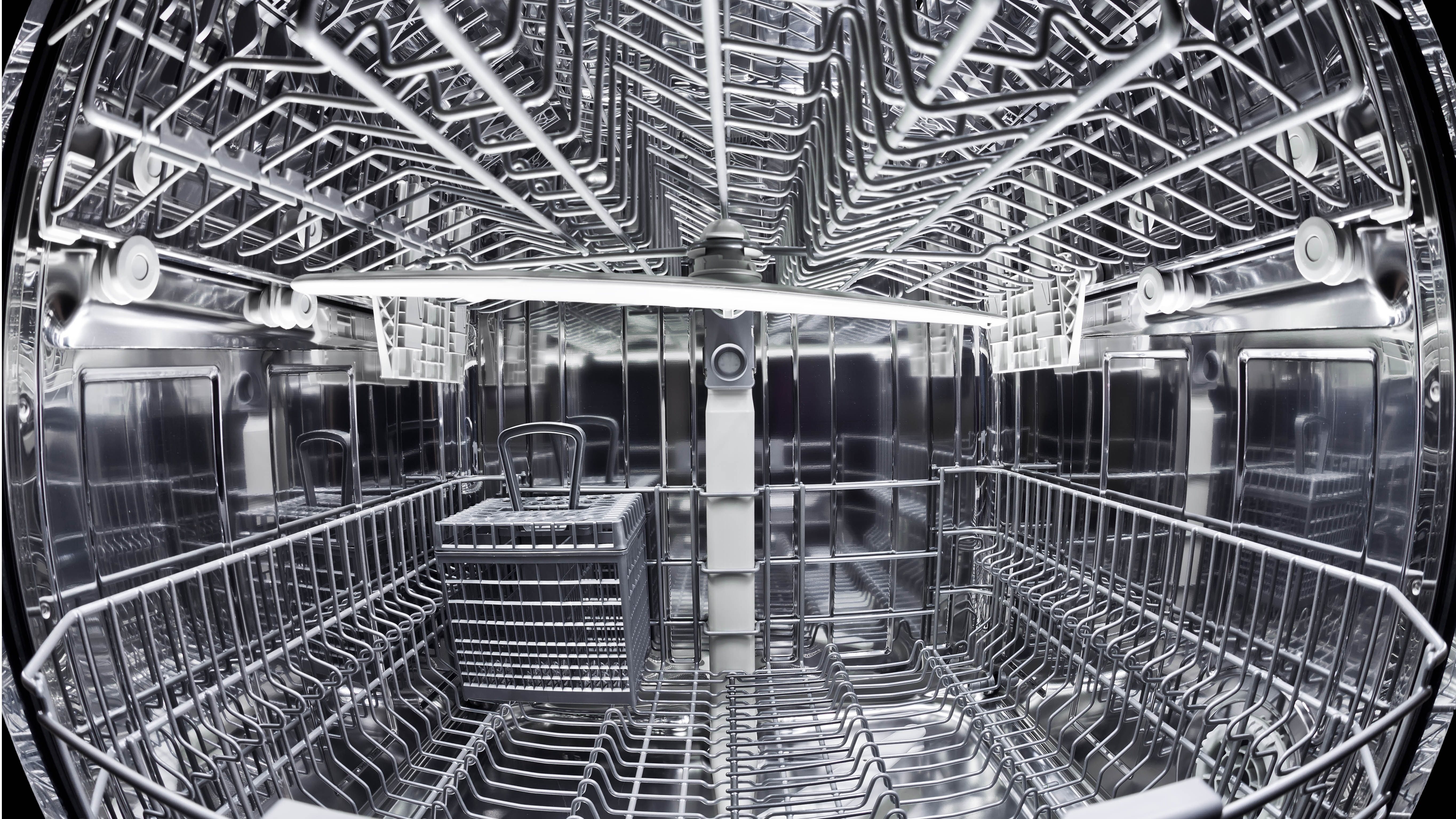 The inside of a dishwasher with upper and lower racks and a cutlery basket