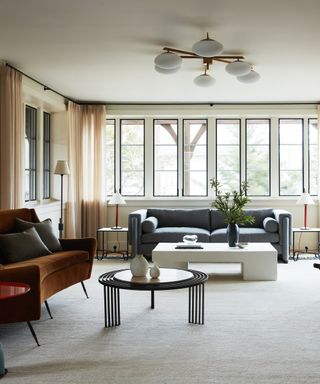 Neutral living room with large windows and gray and brown couch