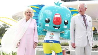 Prince Charles, Prince of Wales and Camilla, Duchess of Cornwall pose with the official mascot Borobi during a tour of the Commonwealth Games Athletes Village