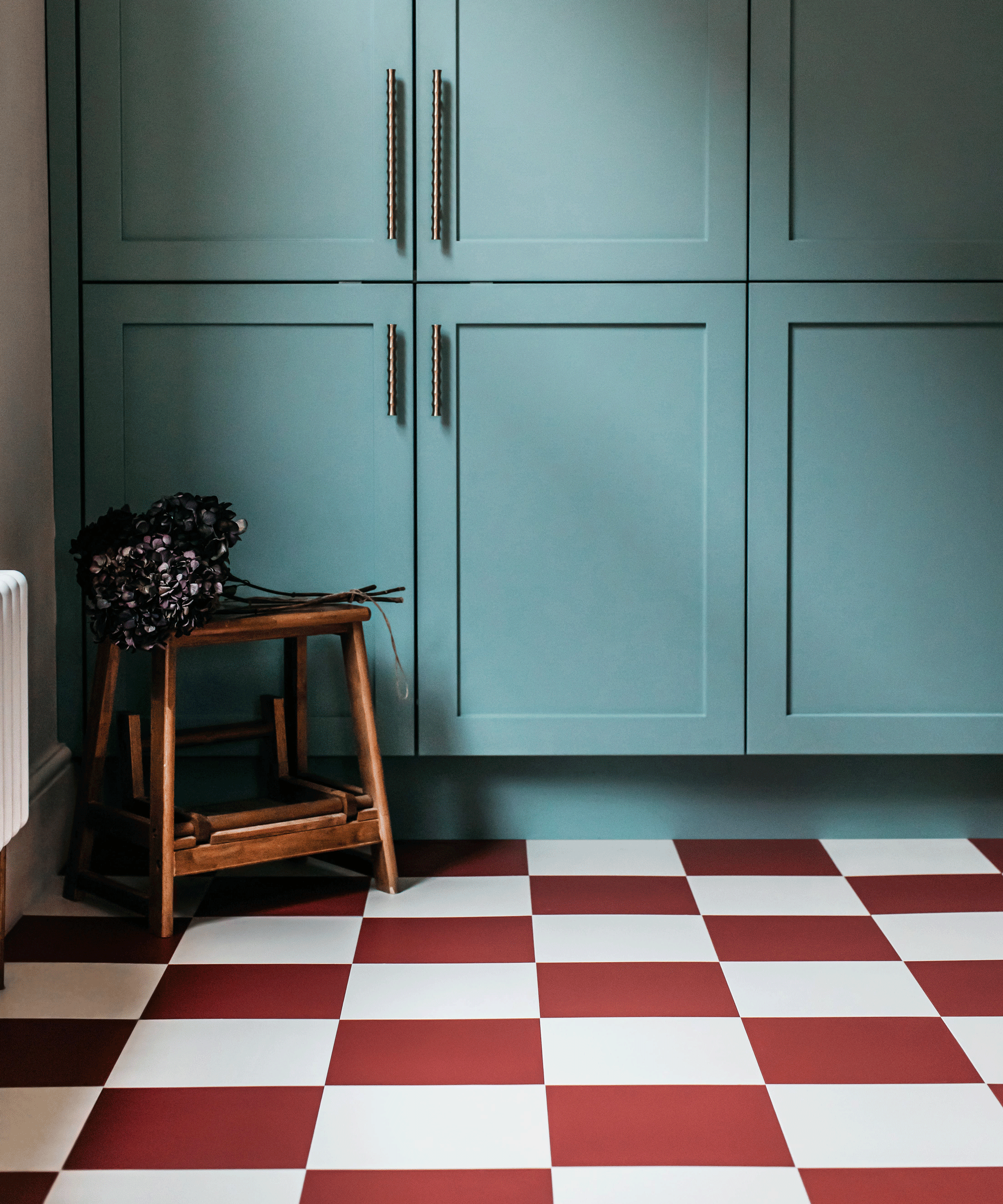 Kitchen with blue cabinetry and red and white chequerboard floor