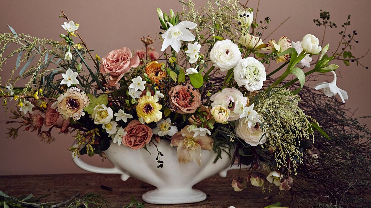 Pink yellow and white flower arrangement in porcelain vase with picture on pink wall