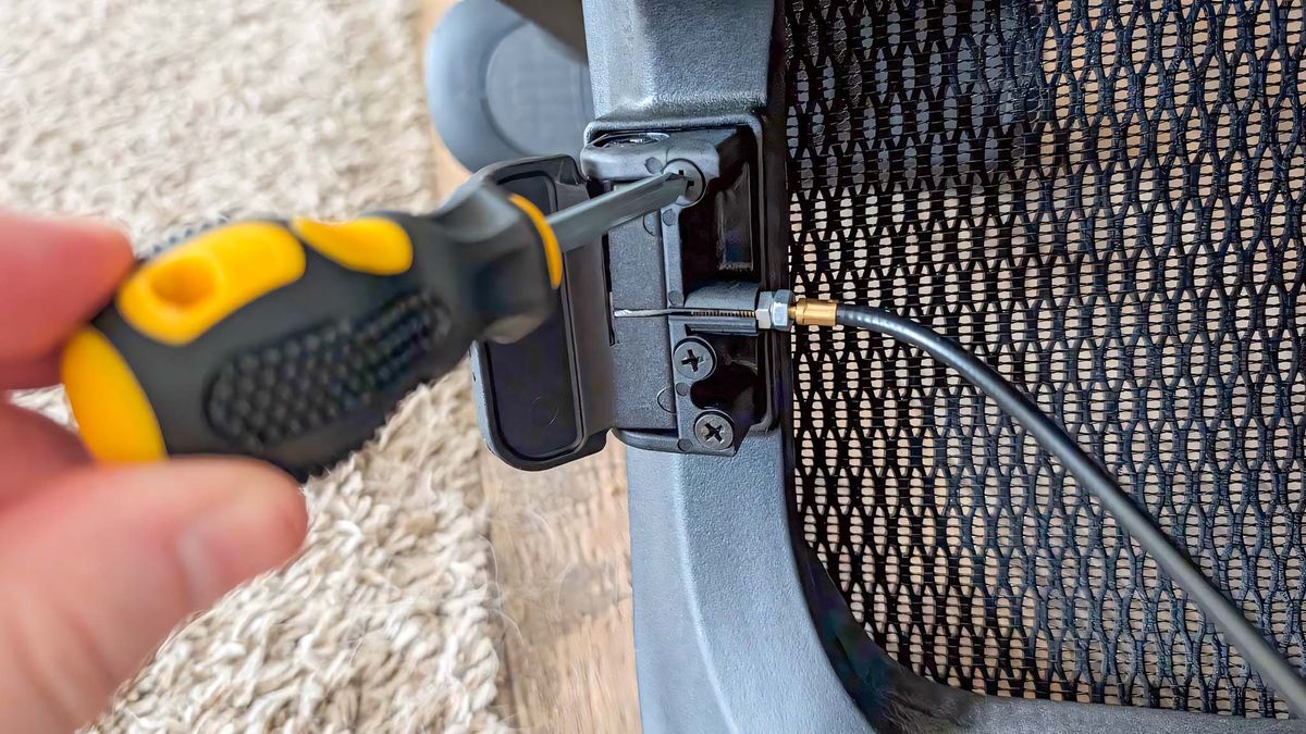 Screwdriving tightening screw to assemble the controls on the buttom of the AndaSeat X-Air Pro Mesh Office Chair.