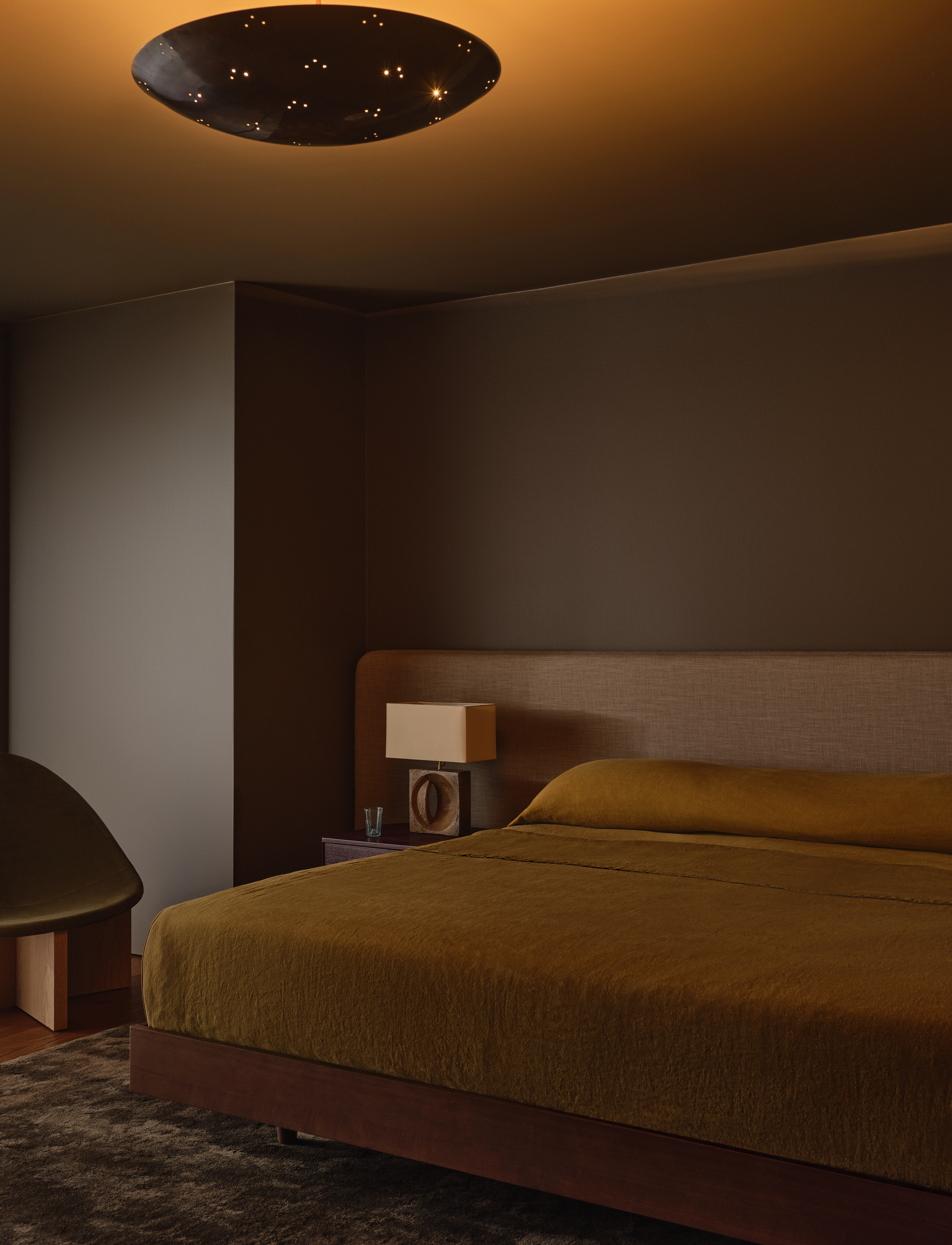 Serene bedroom with minimalist flush mount glowing softly overhead.