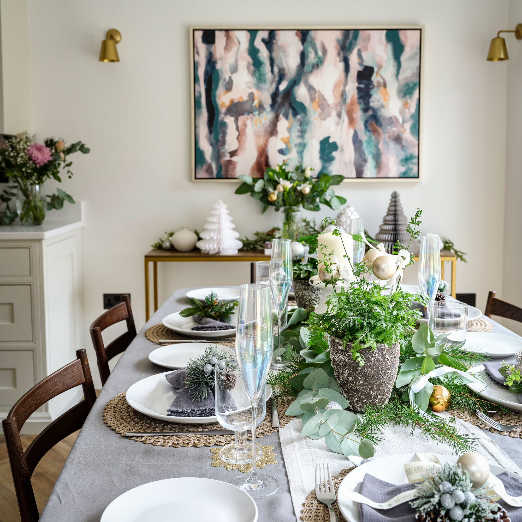 Dining table with pink and green wall art over a console table