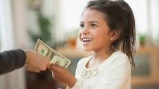 A smiling child accepts a gift of a dollar bill