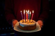 Man holding decorated birthday cake on a plate