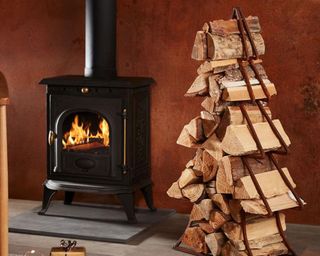 A tree shaped log holder with logs and black woodburning stove