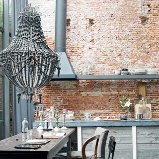 brick wall with chandelier and wooden table with chair